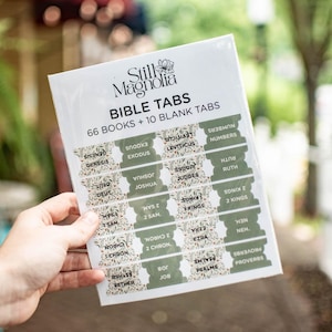 May include: A set of 66 Bible tabs with floral designs and the names of each book of the Bible. The tabs are printed on white paper with green and brown accents. The text "Still Magnolia Bible Tabs 66 Books + 10 Blank Tabs" is printed at the top of the sheet.