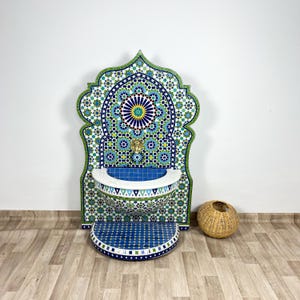 Puede incluir: Una fuente de pared decorativa con un diseño de mosaico azul y verde. La fuente tiene una cuenca de cerámica blanca y un grifo de latón.