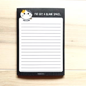 May include: Black notepad with a white lined interior. The notepad has a cartoon cat with the text "I've got a blank space..." and "Mood: Blank" at the top. The bottom of the notepad says "Moodcats".