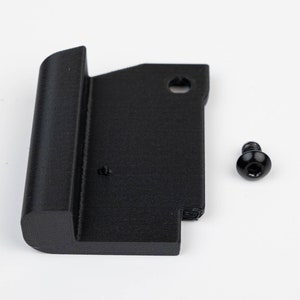May include: A black plastic part with a rounded edge and a hole in the top. A black screw is included.