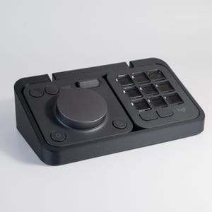 Könnte beinhalten: Ein schwarzes Logitech Stream Deck XL mit einem runden Drehknopf, mehreren Tasten und einem Raster aus 16 anpassbaren LCD-Tasten.