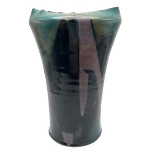 May include: A ceramic vase with a unique, abstract design. The vase is a dark teal color with streaks of purple, black, and white.