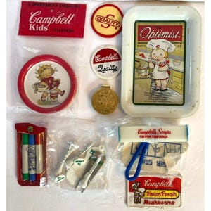 May include: A collection of vintage Campbell's Soup promotional items. Includes coasters, patches, a tray, a pendant, and markers. The items feature the Campbell's Kids and other branding elements. Colors include red, white, gold, and green.