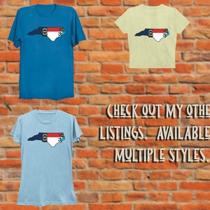 May include: Three t-shirts featuring a North Carolina state outline with the state flag and a blue anchor. The shirts are in blue, light blue, and light yellow. The text "CHECK OUT MY OTHER LISTINGS. AVAILABLE IN MULTIPLE STYLES." is below the shirts.