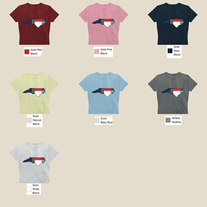 May include: A set of ten t-shirts featuring a graphic of the state of North Carolina with the state flag colors. The shirts are available in a variety of colors, including red, pink, navy, natural, baby blue, heather grey, and white.