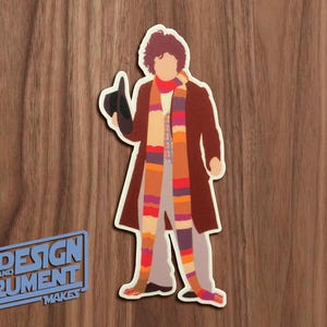 May include: A colorful illustration of a character wearing a long brown coat, a striped scarf, and a hat. The character is standing on a woodgrain background.