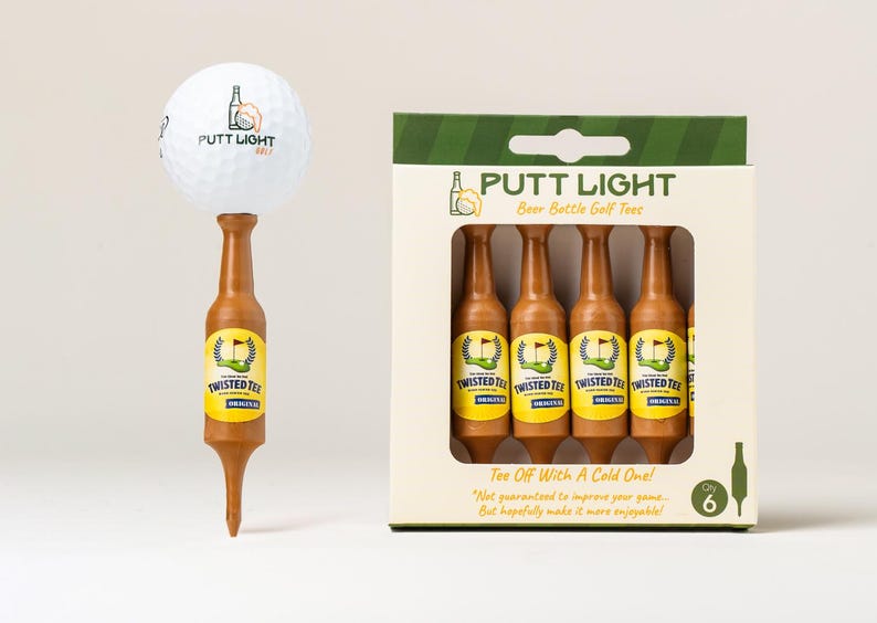 Pu&ograve; includere: Una pallina da golf bianca con il logo Putt Light Golf appoggiata su un tee da golf marrone a forma di bottiglia di birra. Accanto c'&egrave; una scatola di cartone contenente sei tee marroni identici, etichettati Putt Light Beer Bottle Golf Tees, Qty 6.