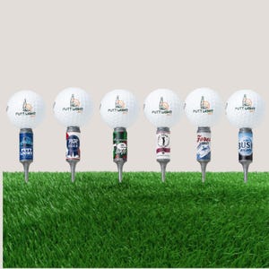 May include: Six golf ball tees with beer can bases. Each white golf ball has the words "PUTT LIGHT" printed on it. The beer can bases include "PUTT LIGHT", "PAR BEER", "Lefty", "Fores Light", and "BUSH RIGHT" labels. The tees are on a green surface.