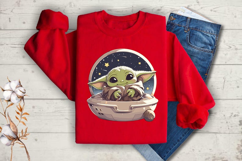 Puede incluir: Sudadera roja con un gr&aacute;fico de un personaje de beb&eacute; alien&iacute;gena verde en una nave espacial sobre un fondo estrellado.