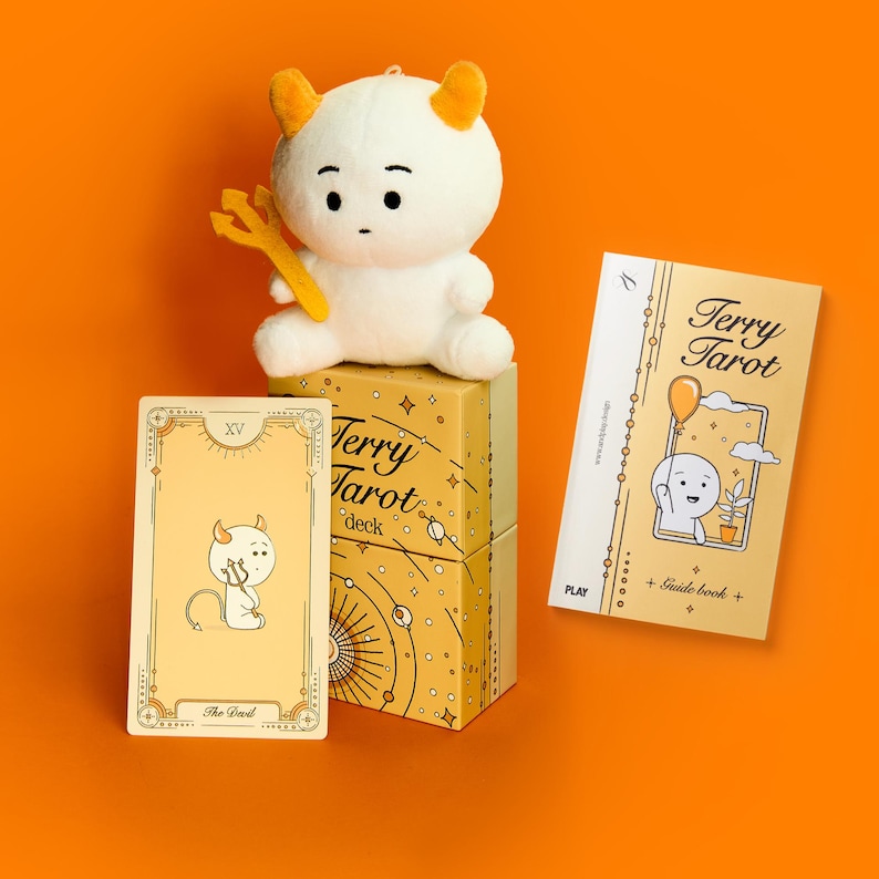 May include: A tarot deck set with a plush devil doll, a card, and a guide book. The deck box and guide book feature the text "Terry Tarot". The card shows a devil illustration, and the doll has horns and a pitchfork.