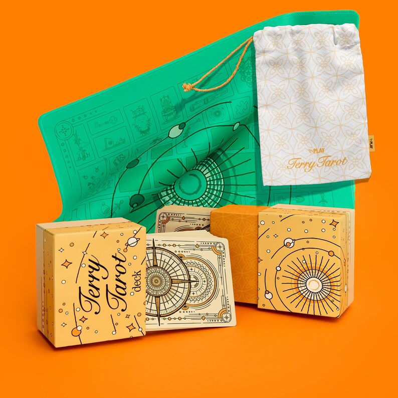 May include: A tarot deck set with a green mat, a drawstring bag, and two boxes. The boxes and bag are cream-colored with gold designs and the text "Terry Tarot". The tarot cards have a compass design.