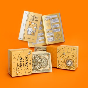 May include: A tarot deck set with a yellow and white color scheme. The set includes a deck of cards, a guide book, and boxes. The text "Terry Tarot deck" is visible on the box and guide book. The background is orange.