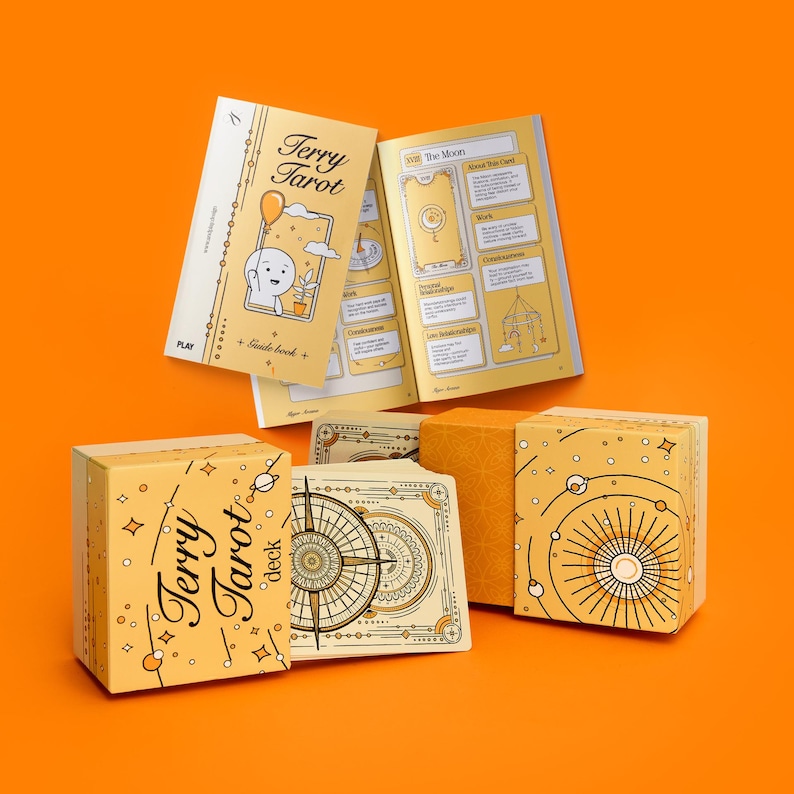 May include: A tarot deck set with a yellow and white color scheme. The set includes a deck of cards, a guide book, and boxes. The text "Terry Tarot deck" is visible on the box and guide book. The background is orange.