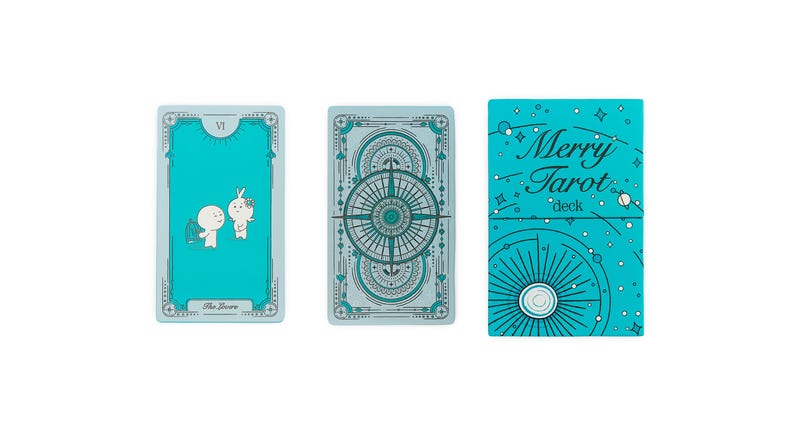 Może przedstawiać: Turkusowa talia Merry Tarot z dwiema kartami tarota i pudełkiem. Karty mają turkusowe tło z białymi i turkusowymi ilustracjami. Na pudełku widnieje napis "Merry Tarot deck" w białym kolorze.