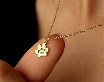 May include: Gold necklace with a small paw print charm that says "Zoe" on it.