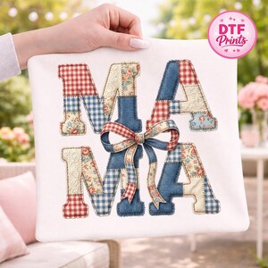 May include: A white square pillow with the word "MAMA" in patchwork letters. The letters are a mix of red gingham, blue denim, floral, and cream-colored lace fabrics. A red and cream bow is centered between the letters.