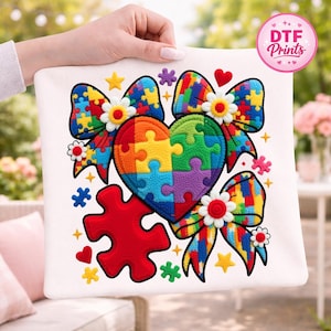 May include: White square fabric with a colorful puzzle heart, bows, and puzzle pieces. The heart and bows are made of puzzle pieces in various colors. The fabric has a DTF Prints logo.