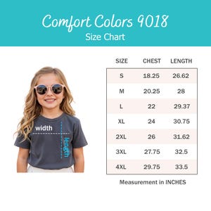May include: A Comfort Colors 9018 size chart featuring a dark grey t-shirt with width and length indicators. The table lists sizes S through 4XL with corresponding chest and length measurements in inches, ranging from 18.25 to 33.5 inches.