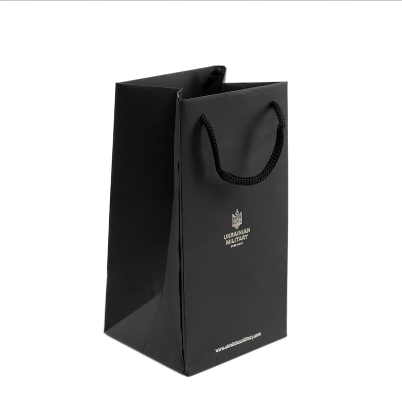 May include: A black paper shopping bag with black handles. The bag has a silver logo that says "UKRAINIAN MILITARY" and a website address.