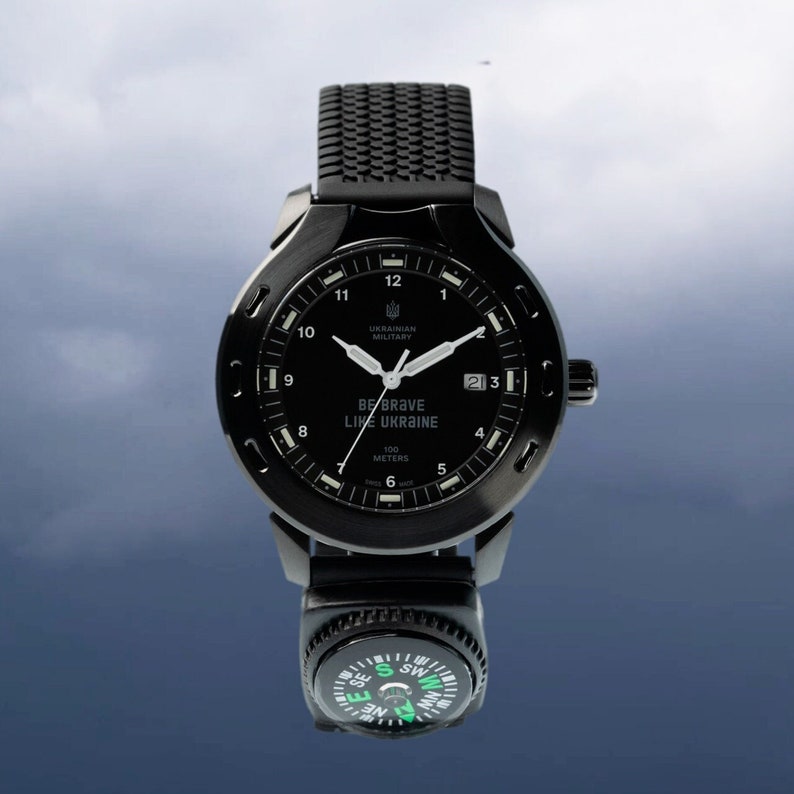 May include: A black wristwatch with a compass attached to the band. The watch face has white markings and the text "BE BRAVE LIKE UKRAINE" and "UKRAINIAN MILITARY".