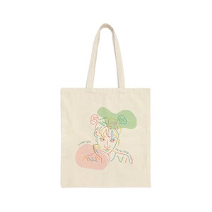 May include: A beige tote bag featuring a colourful line drawing of a person with the text "coder girl" and "never stop coding" on the bag.