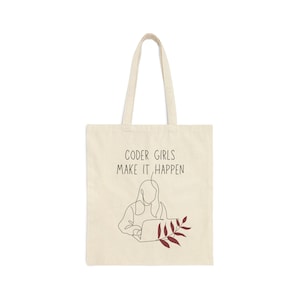 May include: A beige tote bag with the text "CODER GIRLS MAKE IT HAPPEN" printed in black. A line drawing of a person using a laptop is in the centre of the bag. A red leaf branch is to the right of the person.