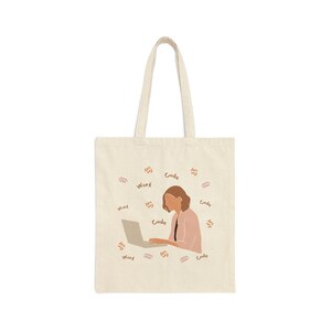 Op de afbeelding: Een beige tote bag met een vrouw die aan een laptop werkt. De tas is versierd met de woorden "Work" en "Code" die herhaald worden rondom de afbeelding.