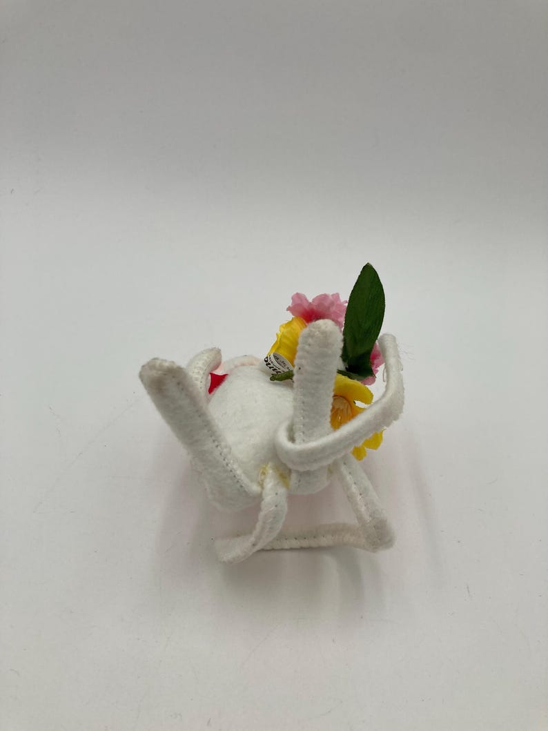 K&ouml;nnte beinhalten: Wei&szlig;e Filzspinne mit gelben und rosa Bl&uuml;ten und gr&uuml;nen Bl&auml;ttern oben.