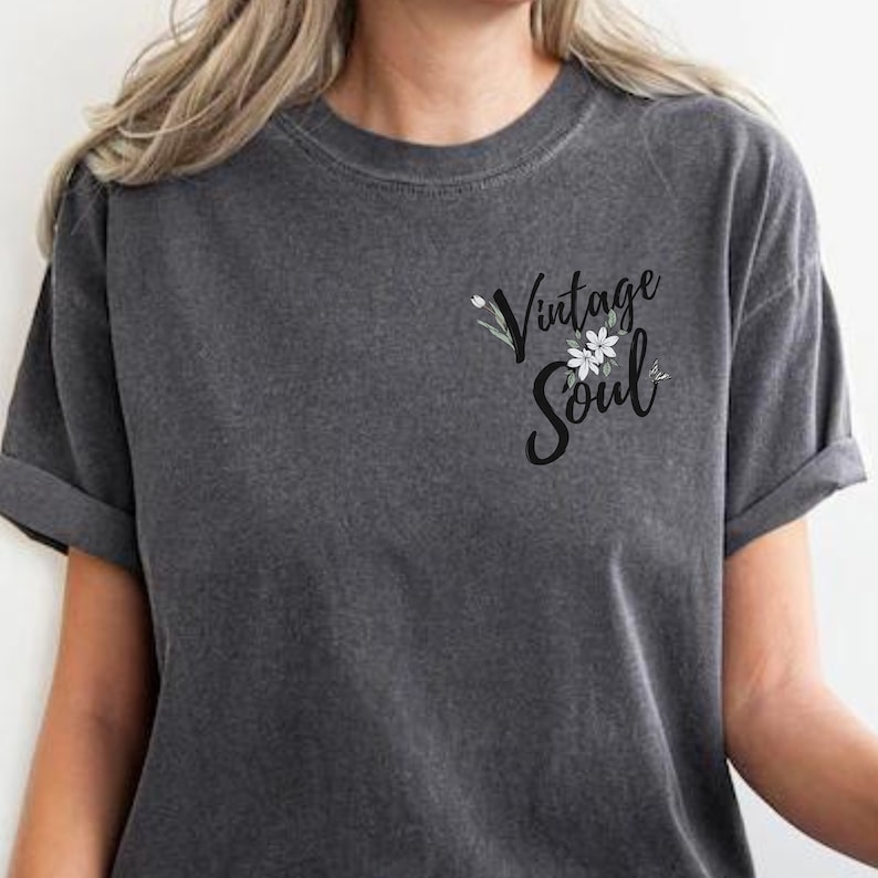May include: A dark gray t-shirt with a vintage soul graphic featuring white flowers and green leaves.