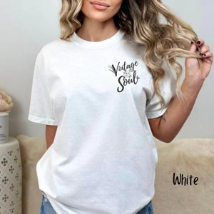 May include: White t-shirt with a floral design and the text "Vintage Soul" printed on the front.