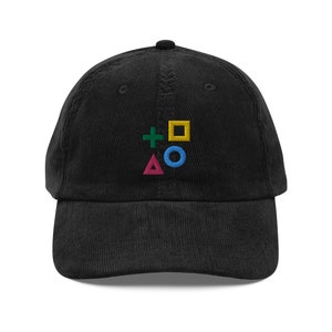 May include: Black corduroy baseball cap with an embroidered design of the PlayStation controller symbols: a green plus sign, a yellow square, a blue circle, and a pink triangle.