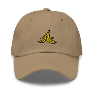 May include: A tan baseball cap with an embroidered yellow banana peel design.
