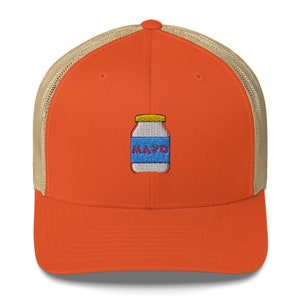 May include: Orange and tan trucker hat with a white jar of mayonnaise embroidered on the front. The jar has a yellow lid and a blue label that says "MAYO" in red letters.