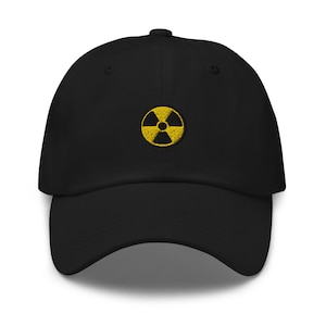 Puede incluir: Gorra de béisbol negra con un símbolo de radiación bordado en amarillo.