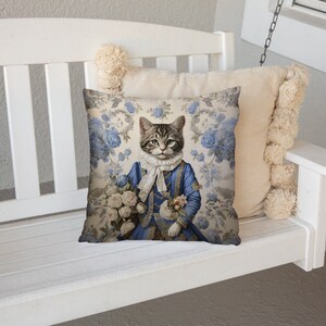 May include: A white swing with a blue and white floral cushion featuring a cat dressed in a blue suit and holding a bouquet of white flowers.