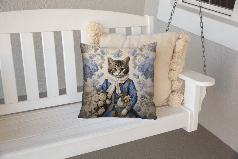 May include: A white swing with a blue and white floral cushion featuring a cat dressed in a blue suit and holding a bouquet of white flowers.