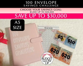 May include: A pink A5 size binder for the 100 Envelope Savings Challenge with white text on the cover. Includes a savings tracker sheet and clear plastic sleeves containing Australian currency notes of $5, $10, and $20 denominations.