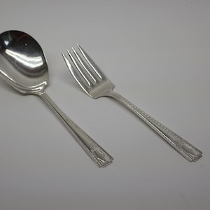 May include: A silver spoon and fork set with a beaded design on the handles.