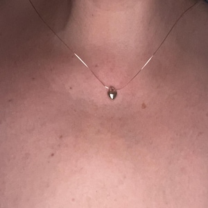 May include: A delicate gold chain necklace with a small heart pendant.