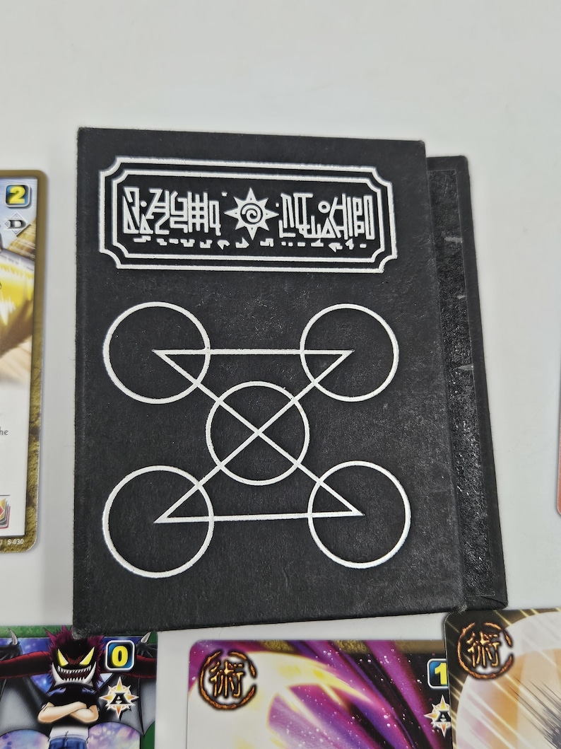 May include: Black card holder with white geometric designs and text. The top of the holder has a rectangular border with symbols and text. Below are four circles connected by lines and triangles.