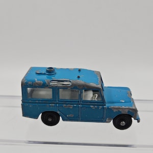 May include: A vintage blue toy car with black wheels. The die-cast model shows signs of wear, with paint chipping on the roof and body. The toy car has a detailed interior and is a classic collectible.