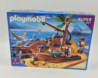 May include: Playmobil Super Set pirate ship toy set. The box features a pirate ship with a shark, palm tree, and pirate figures. The set includes a cannon, anchor, and other pirate-themed accessories. The box has the number 4136.