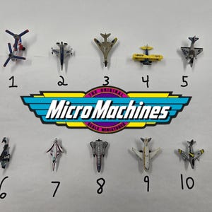 Puede incluir: Una colección de diez aviones y helicópteros de juguete en miniatura Micro Machines. Los juguetes son de varios colores y diseños, incluyendo un helicóptero, aviones de combate y un biplano amarillo. El logotipo de Micro Machines está en el centro.