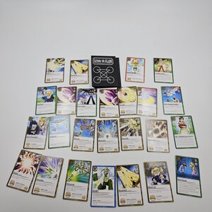 May include: A collection of trading cards featuring various characters and designs. The cards have a gold border and include images of people, symbols, and text. A black card holder with white line art is also present.