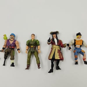 May include: Four plastic action figures of pirate characters. One figure has a parrot on its shoulder and a hook for a hand. Another figure is dressed in green. A third figure is Captain Hook. The fourth figure is a pirate with a yellow vest.
