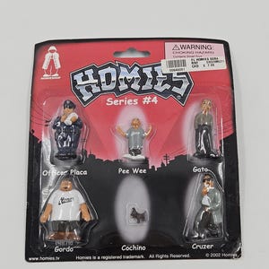 May include: A Homies Series #4 collectible set with six small figurines in a blister pack. The figures include Officer Placa, Pee Wee, Gato, Gordo, Cochino, and Cruzer. The packaging is red and black with the Homies logo.