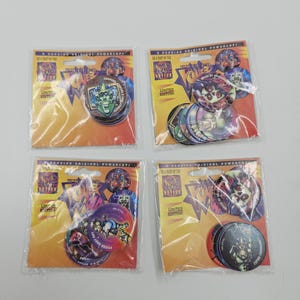 Può includere: Quattro confezioni di Powercaps da collezione, ciascuna contenente più pezzi di gioco circolari. I Powercaps presentano illustrazioni colorate di vari personaggi e la scritta "LIMITED EDITION". La confezione è in plastica trasparente con un retro giallo e arancione.