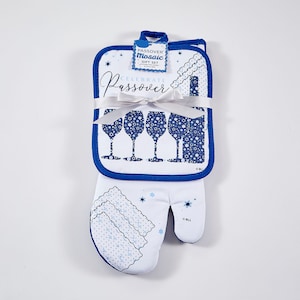 May include: A white oven mitt with a blue trim and a blue and white pattern of wine glasses and stars. The oven mitt is tied with a white ribbon and has a tag that says "Celebrate Passover" and "Passover Mosaic Gift Set".