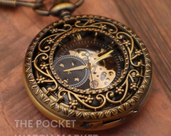 May include: A gold-toned pocket watch with an intricate, ornate design. The watch face is visible through the openwork design and features a skeletonized movement with a black background and gold accents.