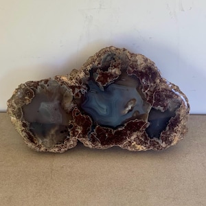 May include: A large, irregularly shaped agate geode with a brown exterior and a blue and white interior. The geode has a natural, rough texture.